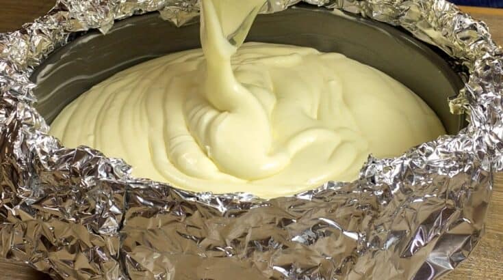 Cheesecake mixture being poured into a springform pan