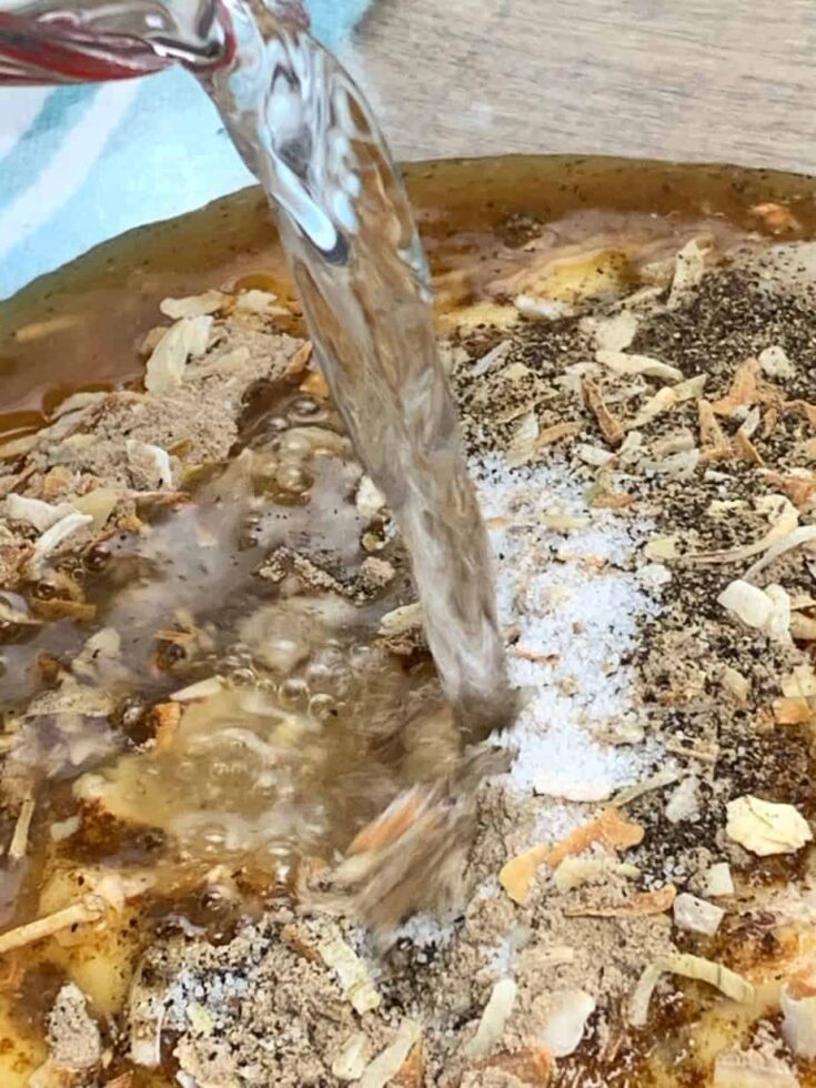 Water being poured into the slow cooker pork shoulder recipe