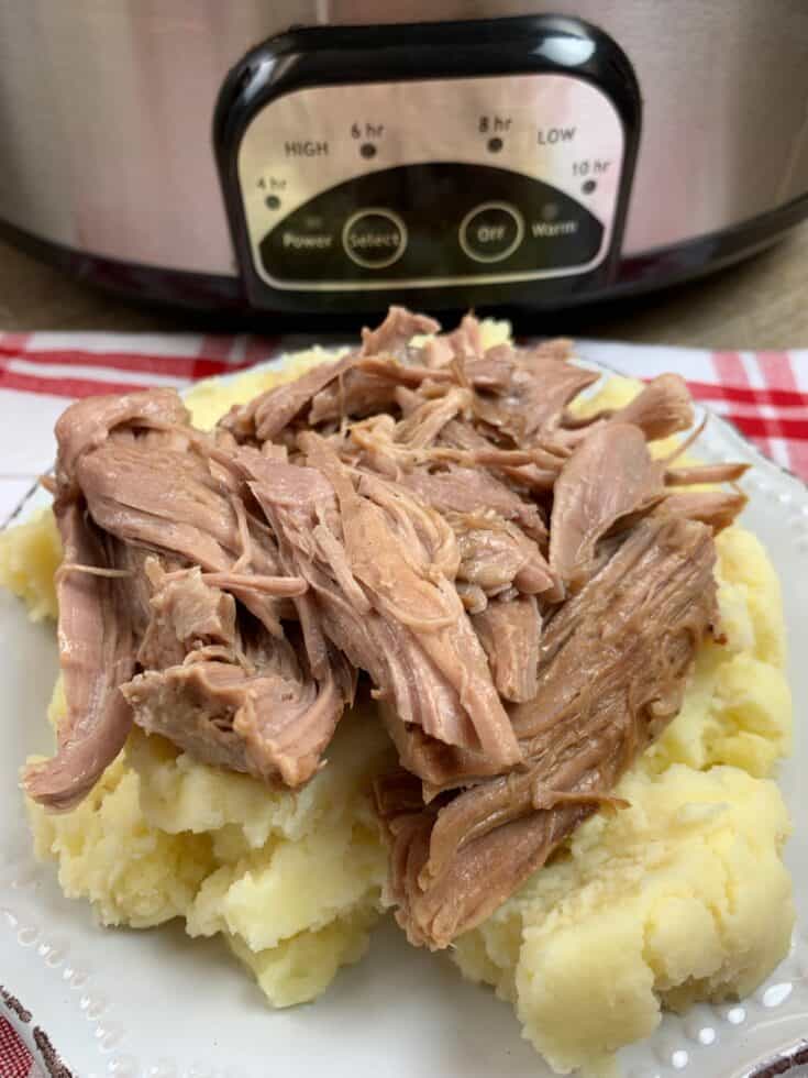 Cooked pork shoulder on a plate on top of mashed potatoes