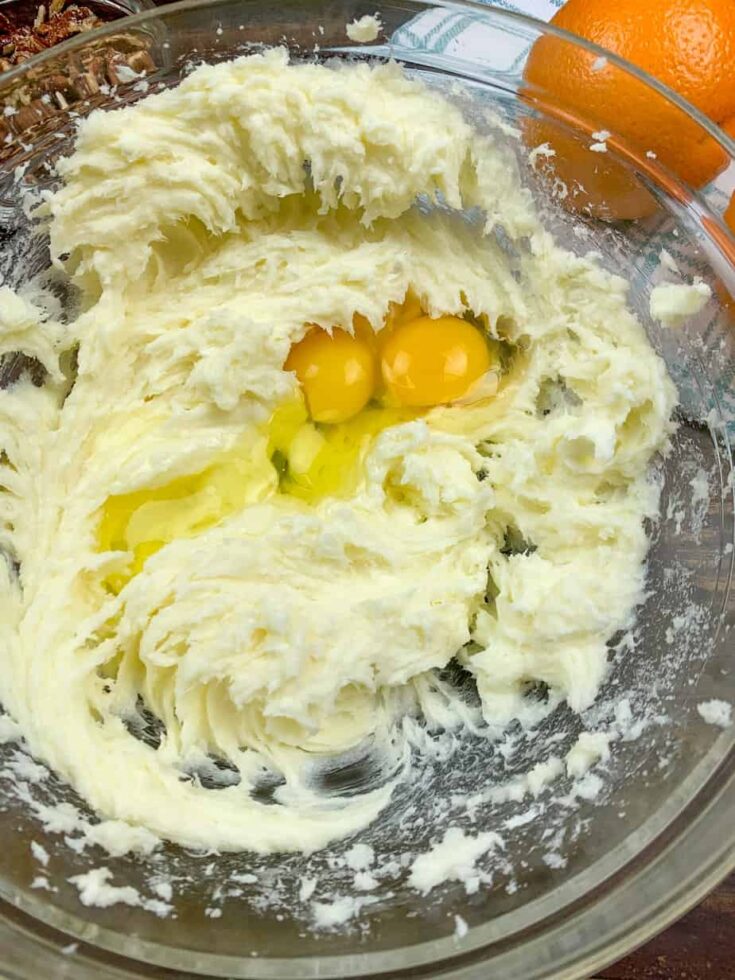 Sugar, cream cheese, butter, and eggs mixed together in a glass bowl