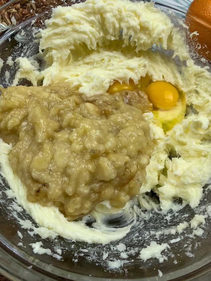 Mashed bananas along with eggs, sugar, butter, and cream cheese in a bowl