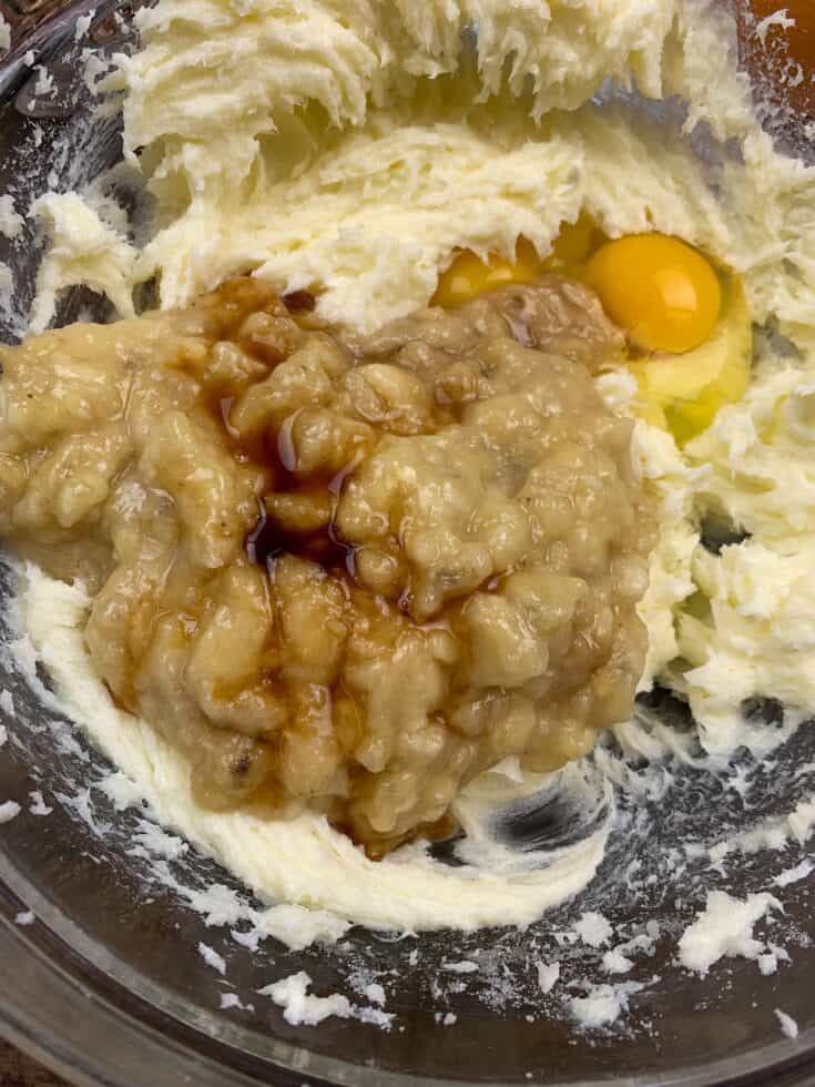 Vanilla extract, mashed bananas, eggs, sugar, butter. and cream cheese mixed up in a bowl