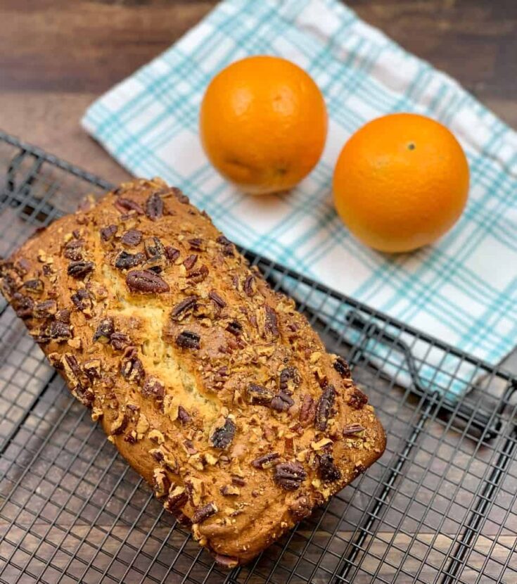 Baked banana bread on a cooling rack with oranges.