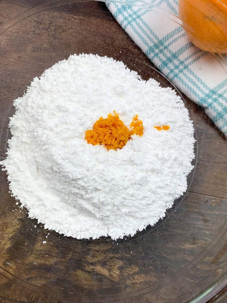 Orange zest and powdered sugar in a glass bowl