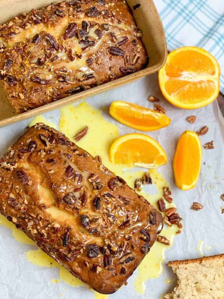 Two loaves of banana nut bread on a counter with orange slices