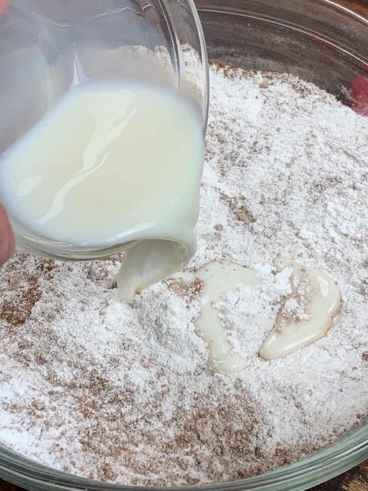 Milk being poured into a bowl with powdered sugar and cocoa