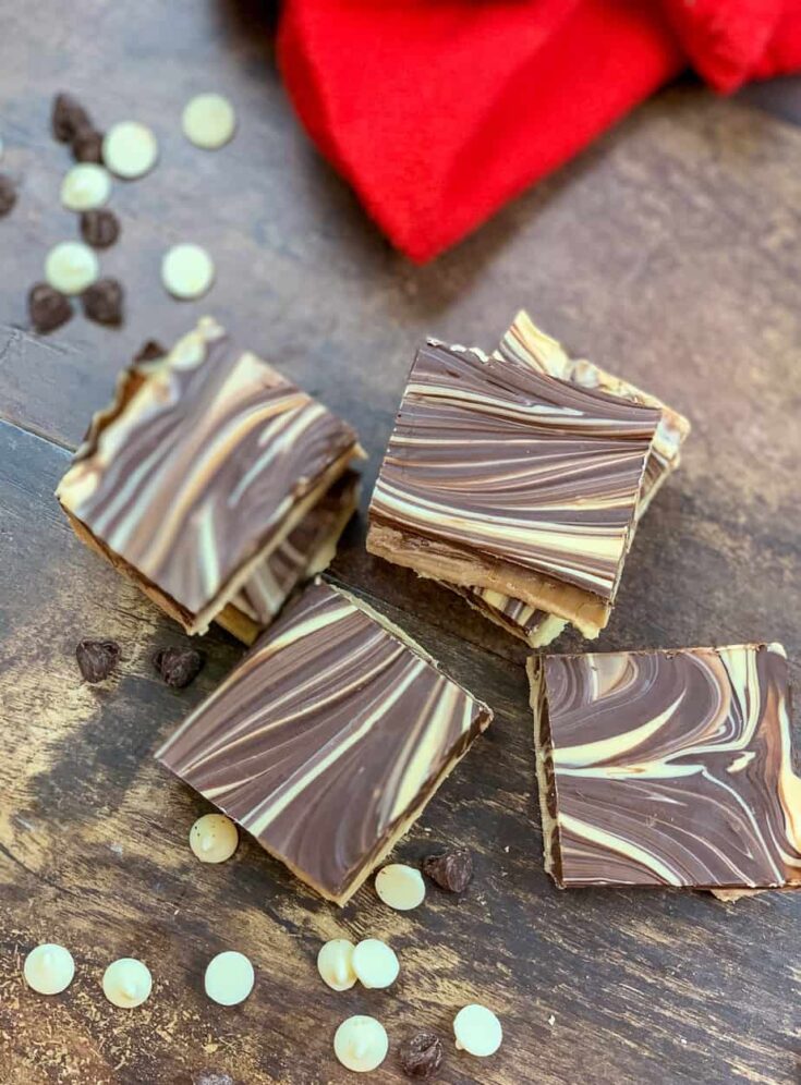 Tiger butter fudge with chocolate chips and a red kitchen towel on the counter.