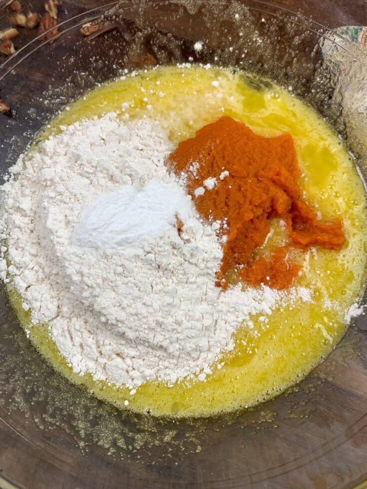 Pumpkin, flour, eggs, and sugar in a glass bowl