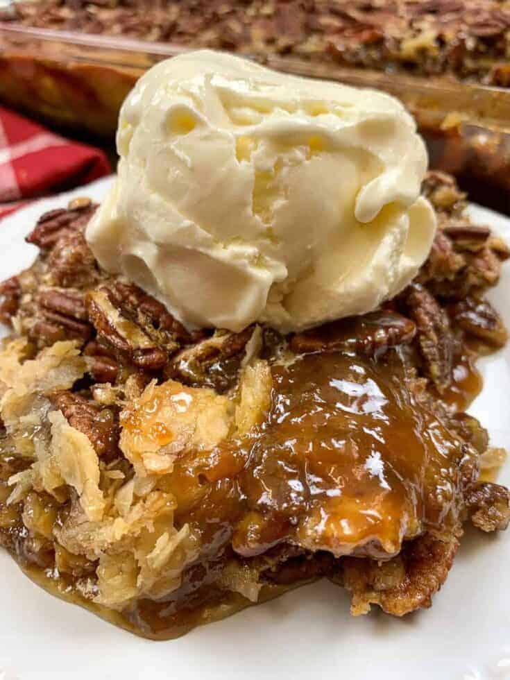 Pecan pie cobbler on a white plate with a scoop of ice cream