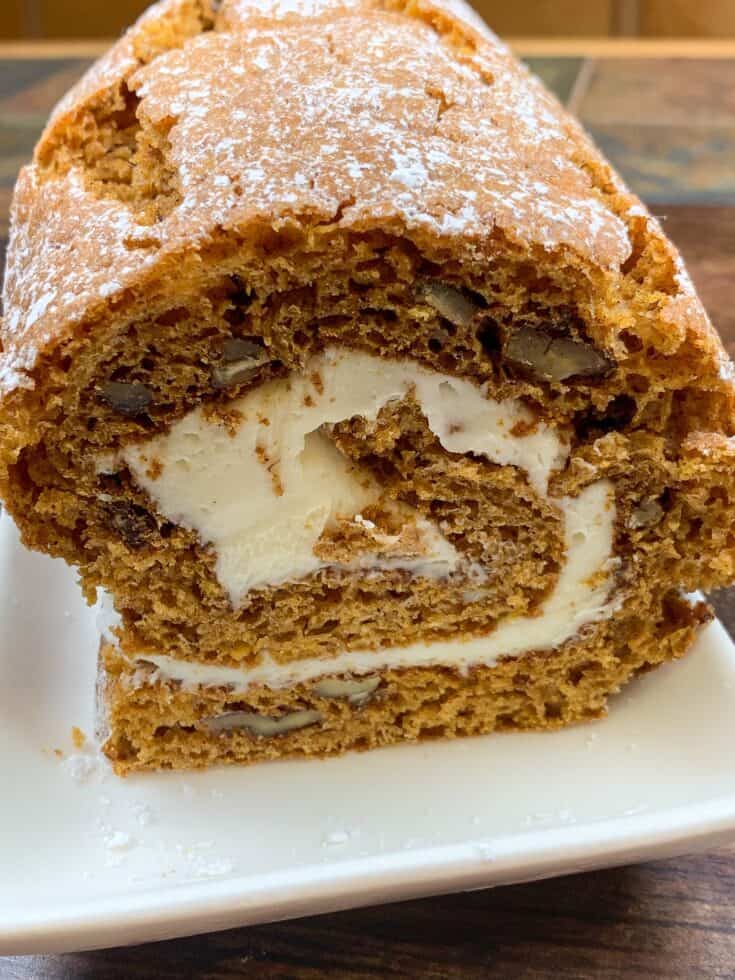 Sliced pumpkin roll with cream cheese frosting on a plate