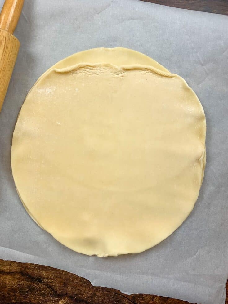 Two pie crusts rolled out on parchment paper 