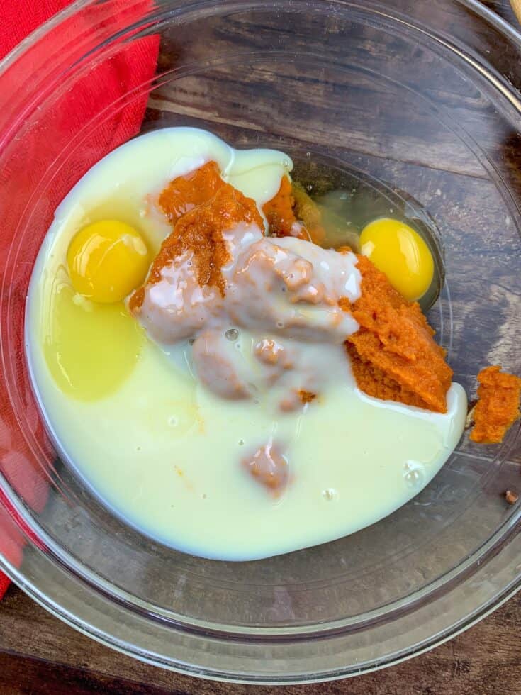 Eggs, sweetened condensed milk, pumpkin puree, and brown sugar in a glass bowl