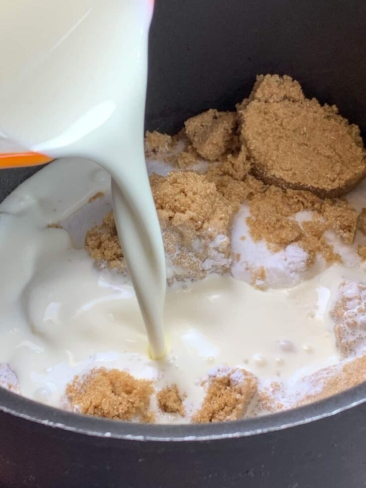 Pouring heavy cream into a saucepan with brown and white sugar.