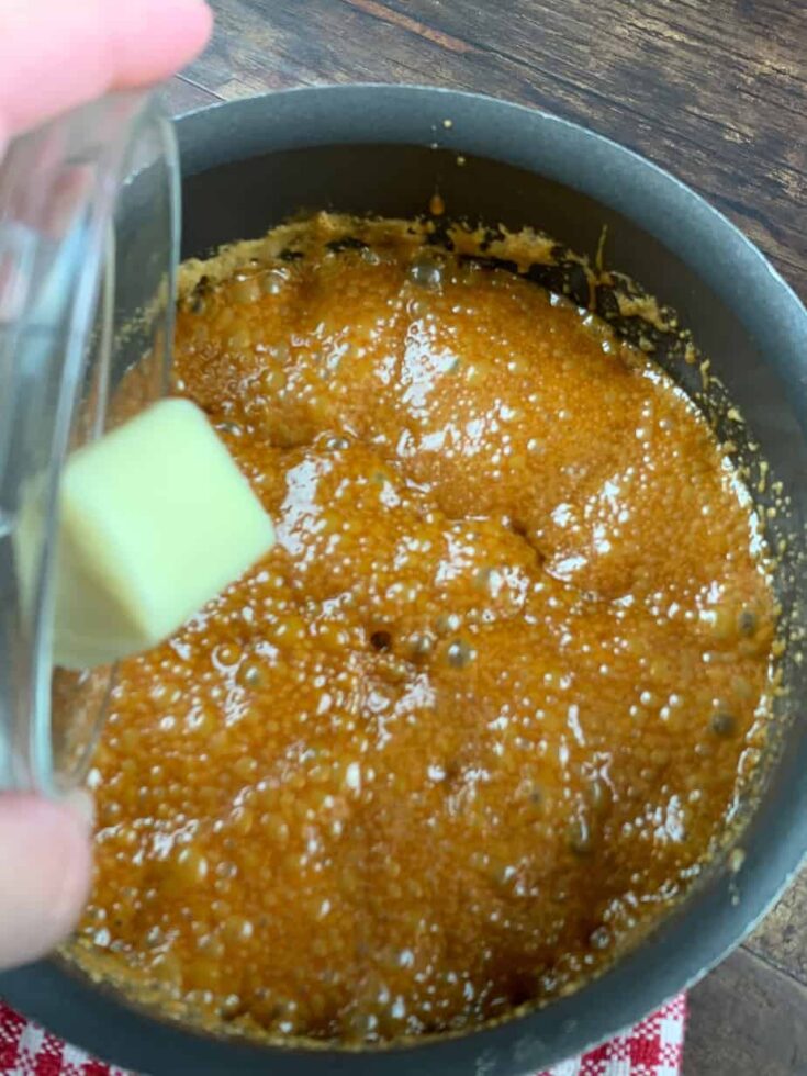 Butter falling into a saucepan with boiling sugar