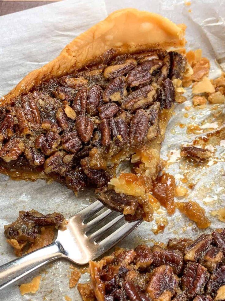 A slice of pecan pie on a piece of parchment paper. 