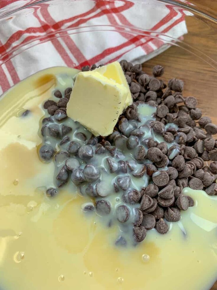 Butter, chocolate chips, and sweetened condensed milk in a glass bowl