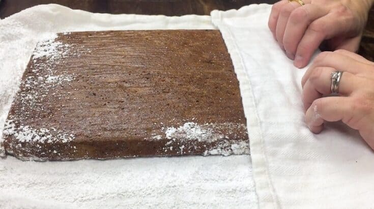 Rolling up the pumpkin roll on a towel covered with powdered sugar