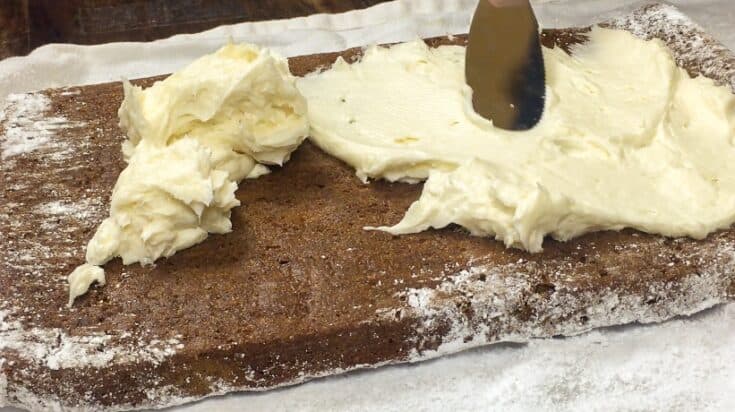 Spreading cream cheese frosting inside of the pumpkin roll