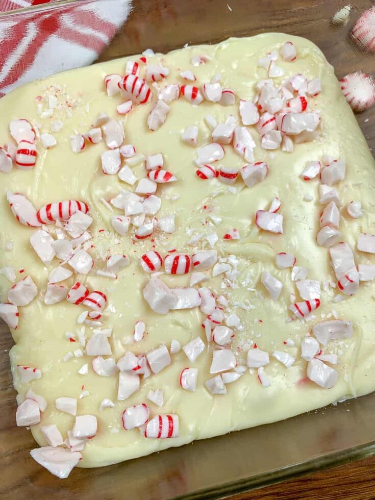 Peppermint chocolate fudge in a glass dish with peppermint candies on top