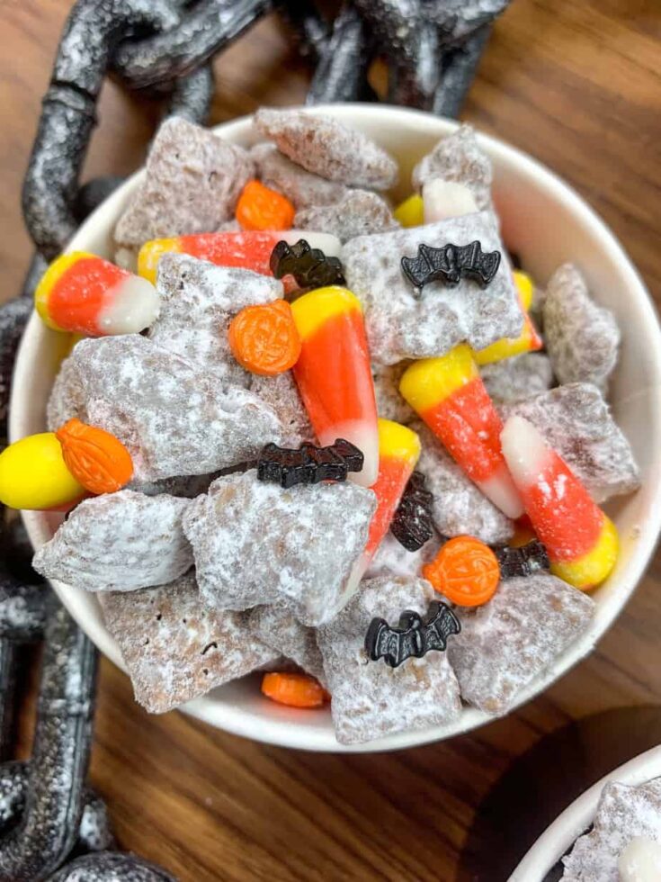 Candy corn, pumpkin and bat candy, and muddy buddies in a container. 