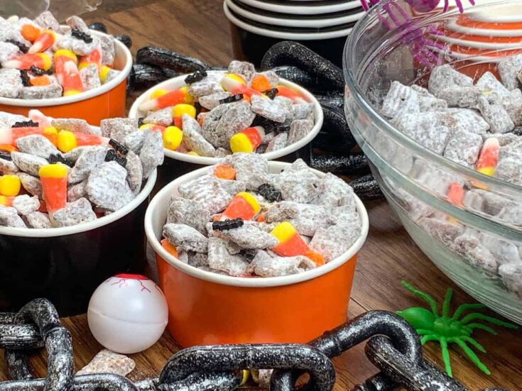 Halloween Muddy Buddies in containers on the counter with Halloween decorations