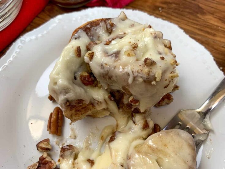 Cinnamon roll on a plate with cream cheese frosting.