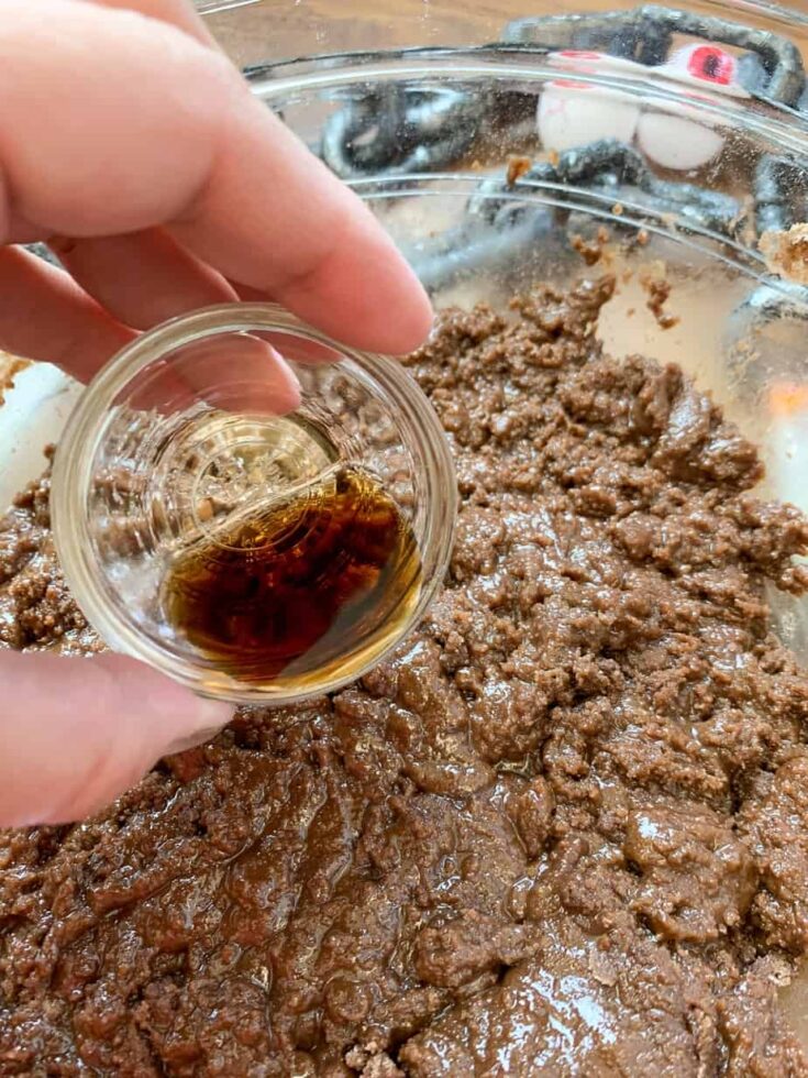 Vanilla extract being poured into cake batter