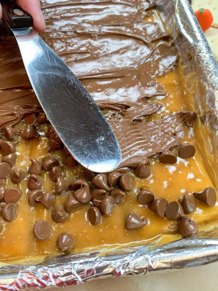 Chocolate chips being spread out over toffee 