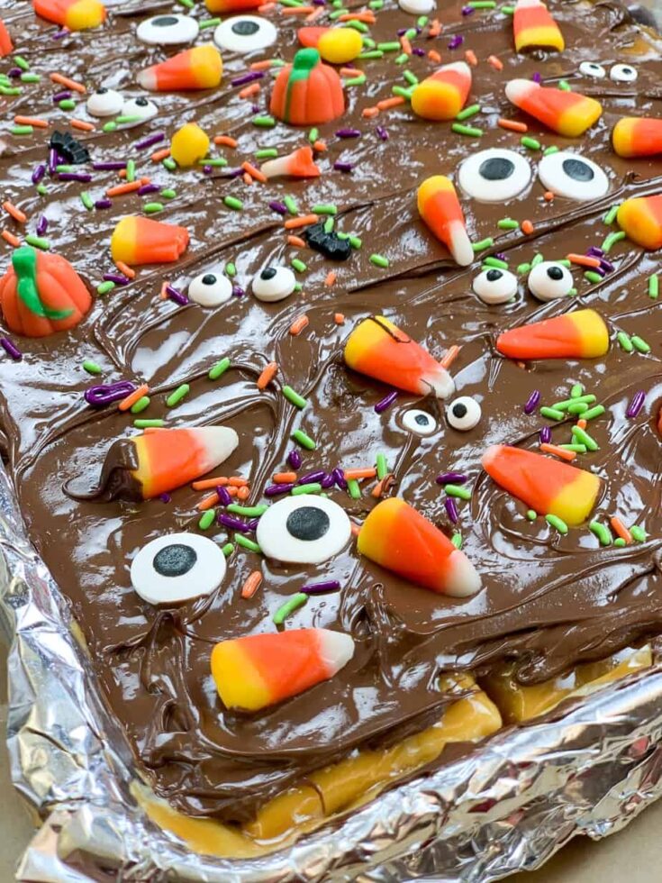 Halloween candy sprinkled on top of chocolate, toffee, and crackers