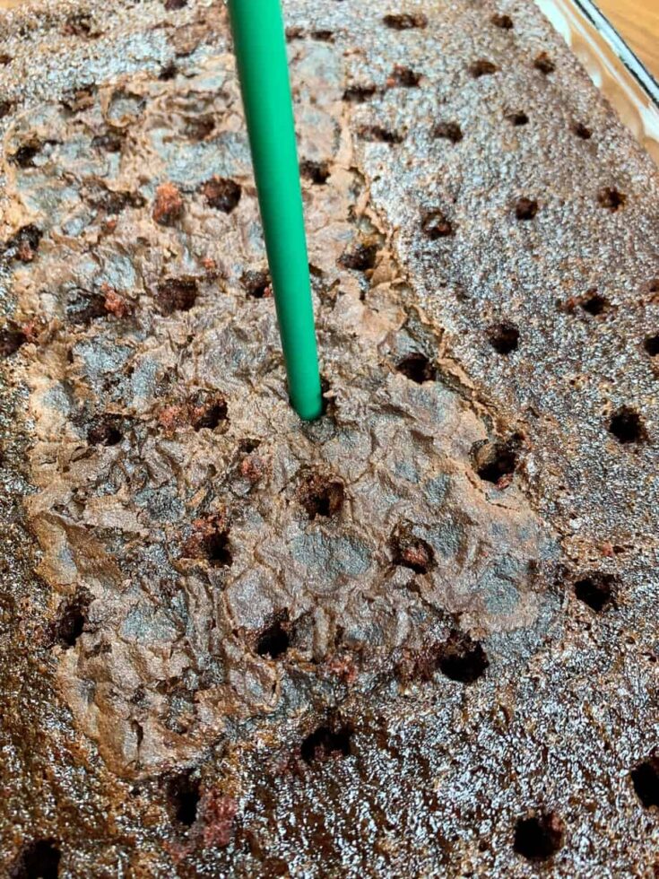 Poking holes in a chocolate cake with a straw