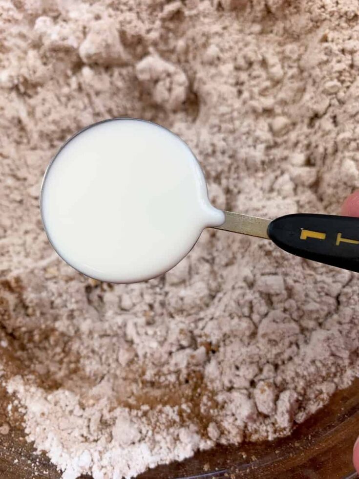 Milk being poured into a bowl of powdered sugar and cocoa