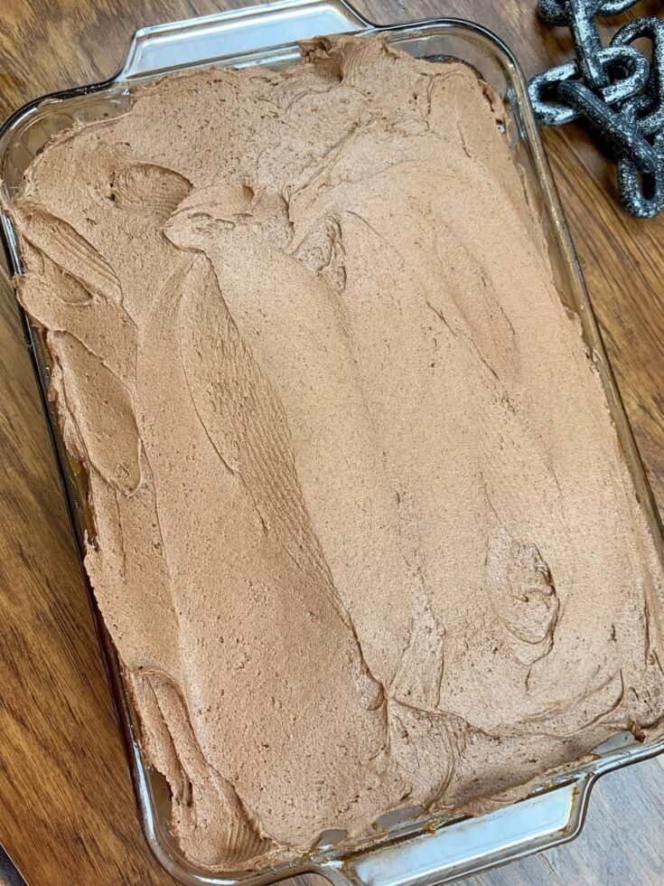 Chocolate frosting spread over a chocolate cake