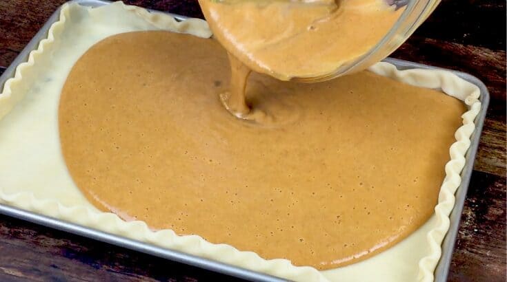 Pouring pumpkin pie filling into a pie crust