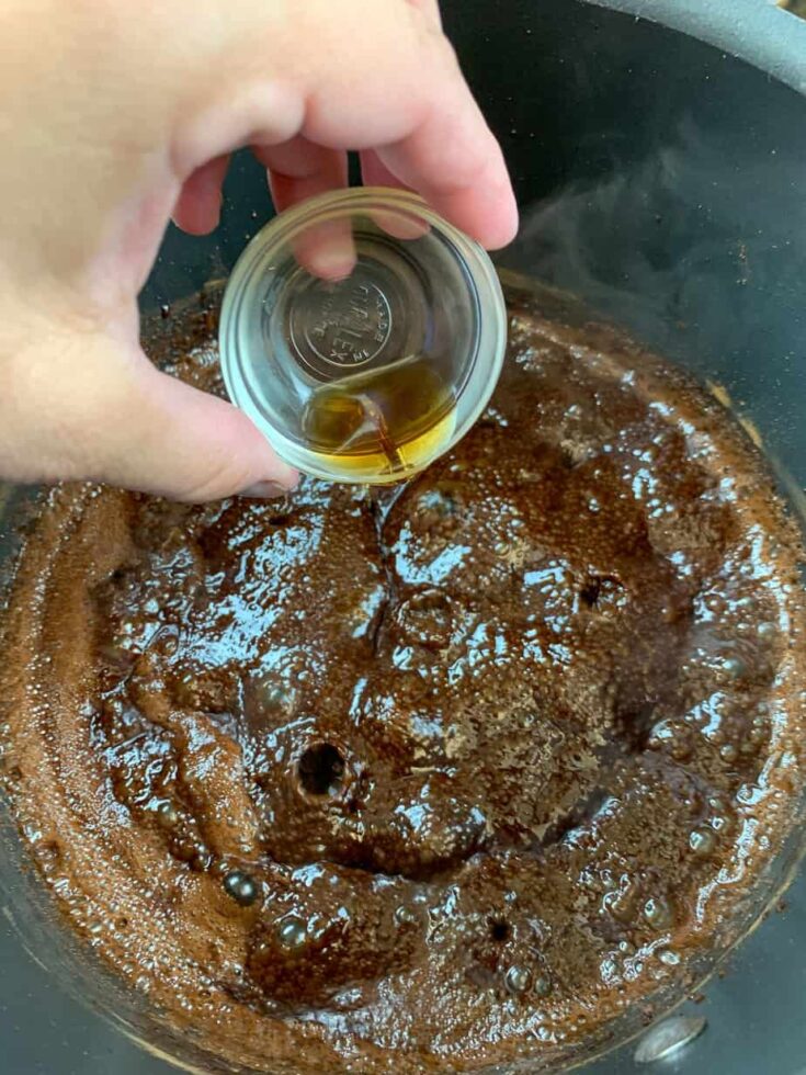 Pouring vanilla extract into the fudge. 