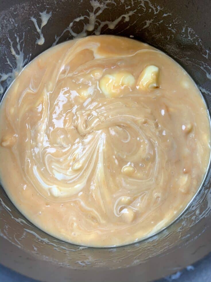 Peanut butter, sweetened condensed milk, butter, and white chocolate chips melting in a saucepan