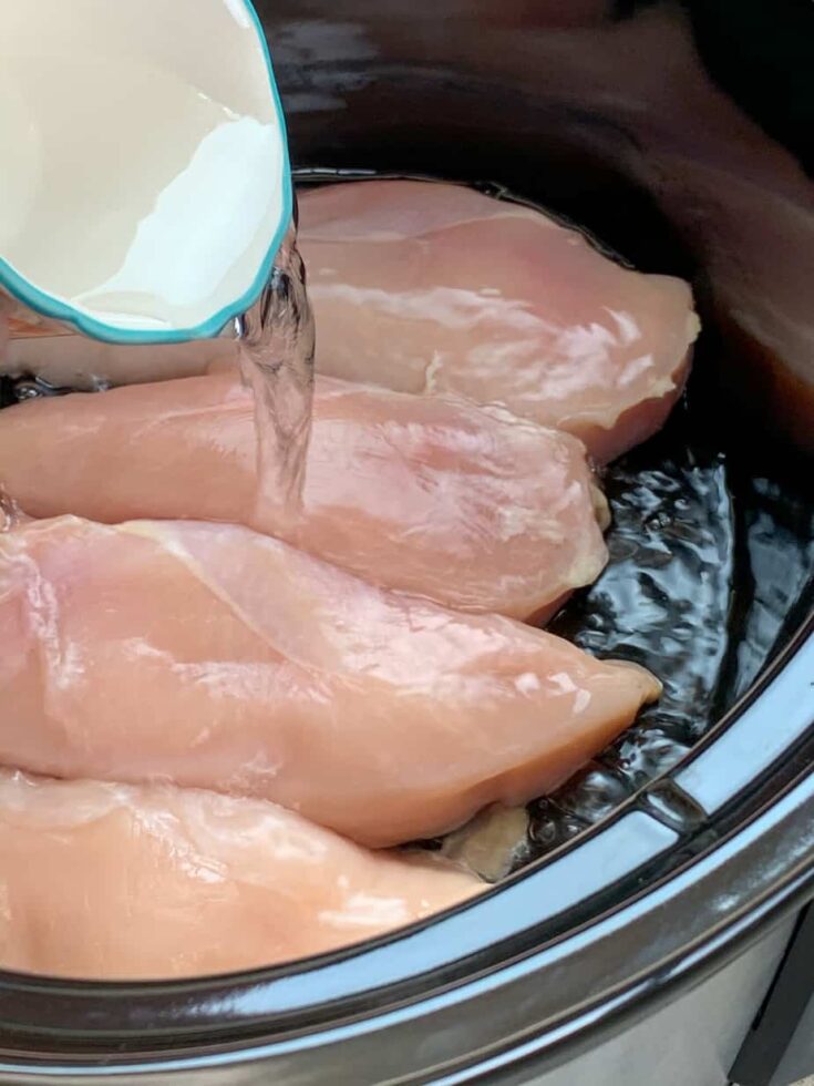 Pouring water over chicken in a Crock Pot