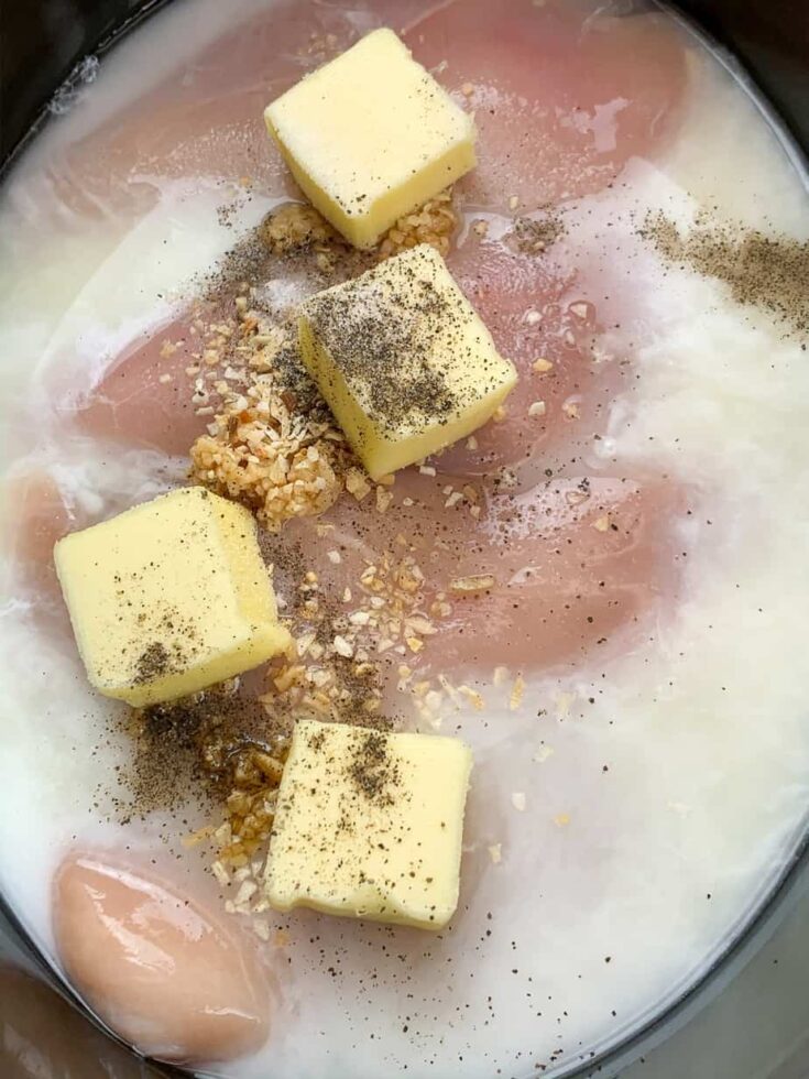 Cubed butter, salt and pepper, onion, and garlic over chicken in a crock pot