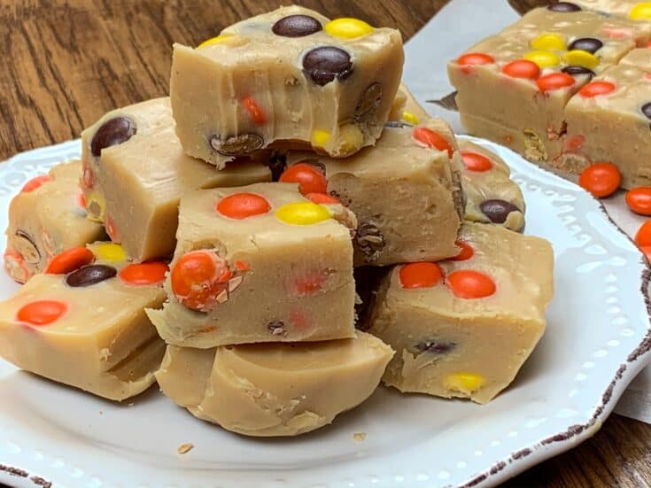 Reese's Pieces peanut butter fudge cut up and stacked on a white plate