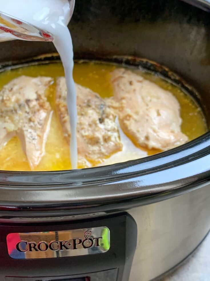 Pouring water and cornstarch into a Crock Pot over chicken