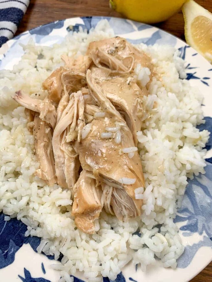 Shredded chicken and rice on a plate with lemons to the side