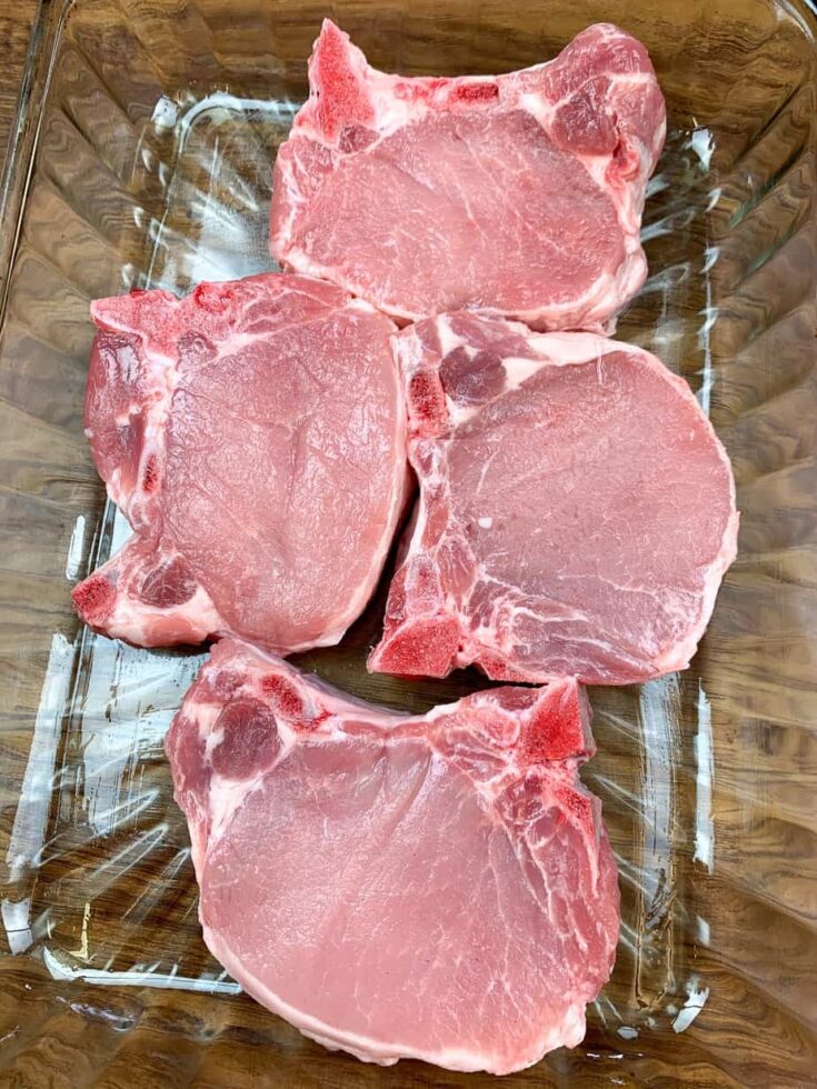 Four pork chops in a glass casserole dish