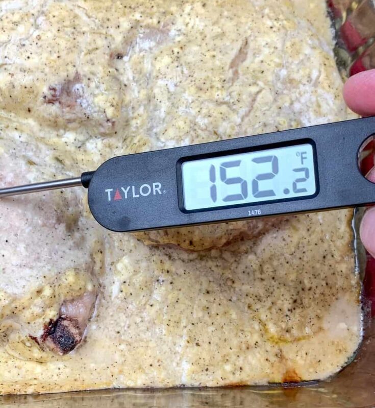 A digital thermometer resting inside of cooked pork chops with gravy