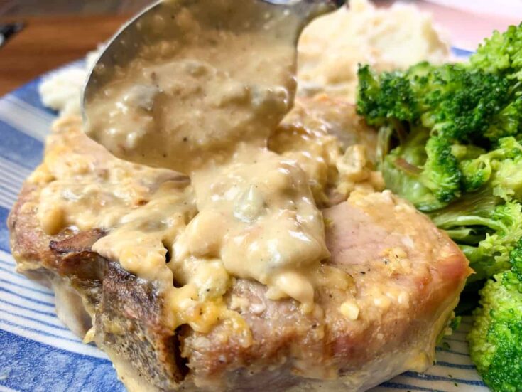 Gravy being spread over smothered pork chops