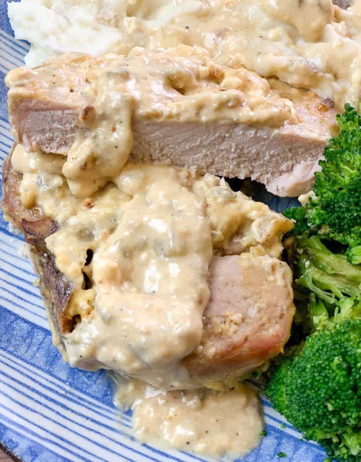 Pork chops and gravy cut up on a blue and white striped plate