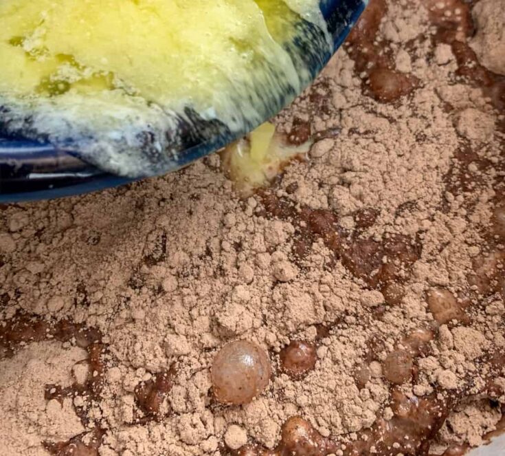 Pouring melted butter into the Crock Pot with chocolate cake mix. 