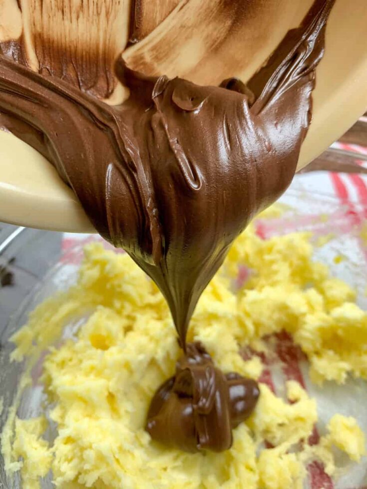 Pouring melted chocolate into a bowl with butter and sugar