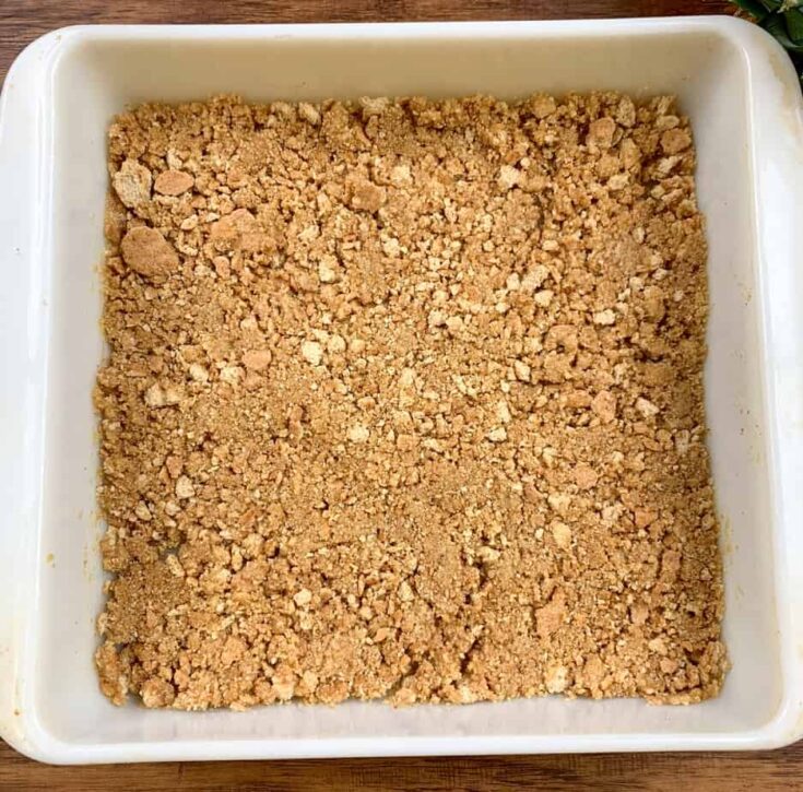 Graham crackers crushed and pressed into a casserole dish