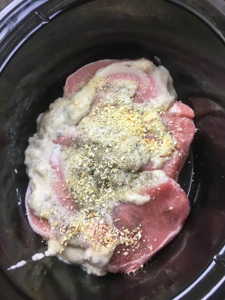 Pork chops in the slow cooker with mushroom soup and spices on top. 