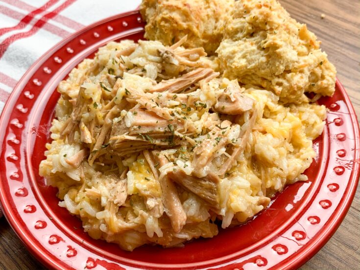 Pork chops and rice on a red plate with biscuits