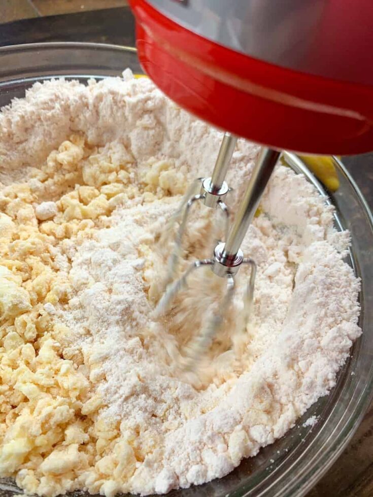 Mixing the cake mix, lemon, and butter in a glass bowl with a hand mixer.